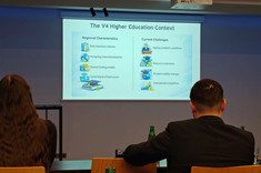 Dwie osoby widoczne od tyłu, siedzące przed slajdem w trakcie dyskusji konferecyjnej, na slajdzie tytuł: The V4 Higher Education Context, zdj. udostępnione przez uczestników