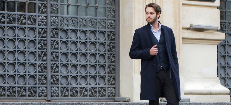 Zdjęcie przedstawia elegancko ubranego mężczyznę schodzącego w dół schodów,