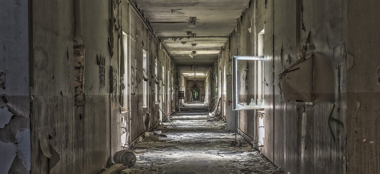 Fotografia przedstawia długi korytarz, pełen zniszczeń, zdewastowany, symbolizujący niszczącą siłę korupcji w organizacji.