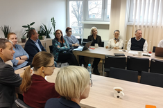 Na zdjęciu uczestnicy spotkania siedzący przy stołach ustawionych w literę U, 