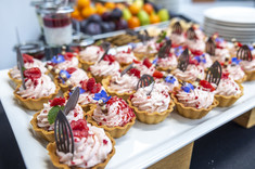 Na zdjęciu desery i owoce na stołach z cateringiem,