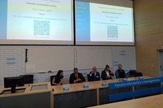 Na zdjęciu 5 osób za stołem konferencyjnym podczas sesji plenarnej. Nad nimi na ekranie widać dane konferencji , fotografia ze zbiorów własnych uczestniczek